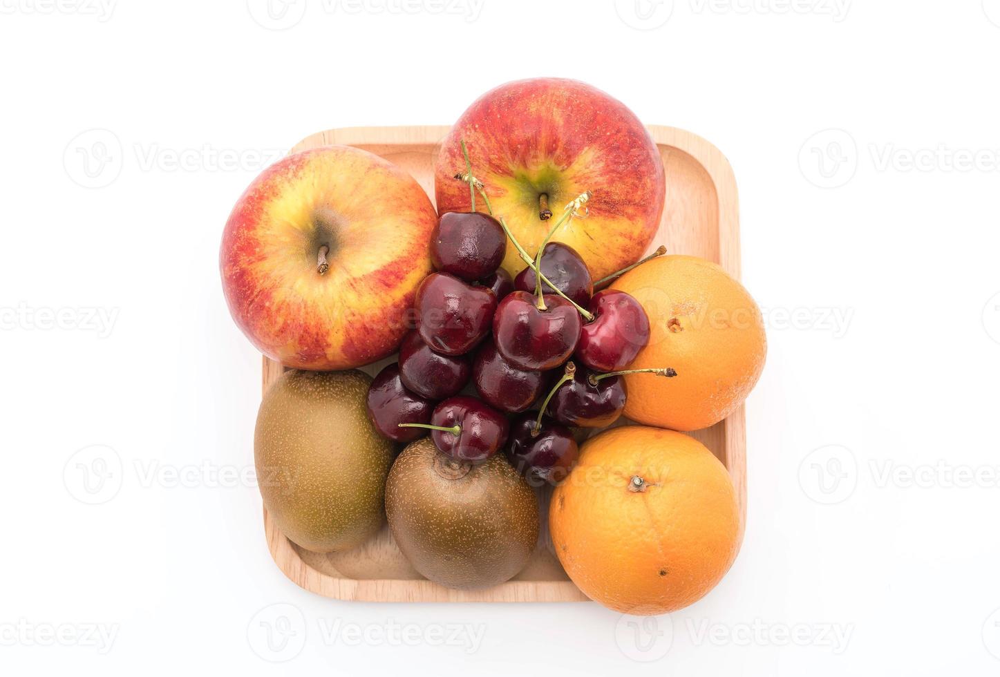 frutta mista in piatto di legno su sfondo bianco foto