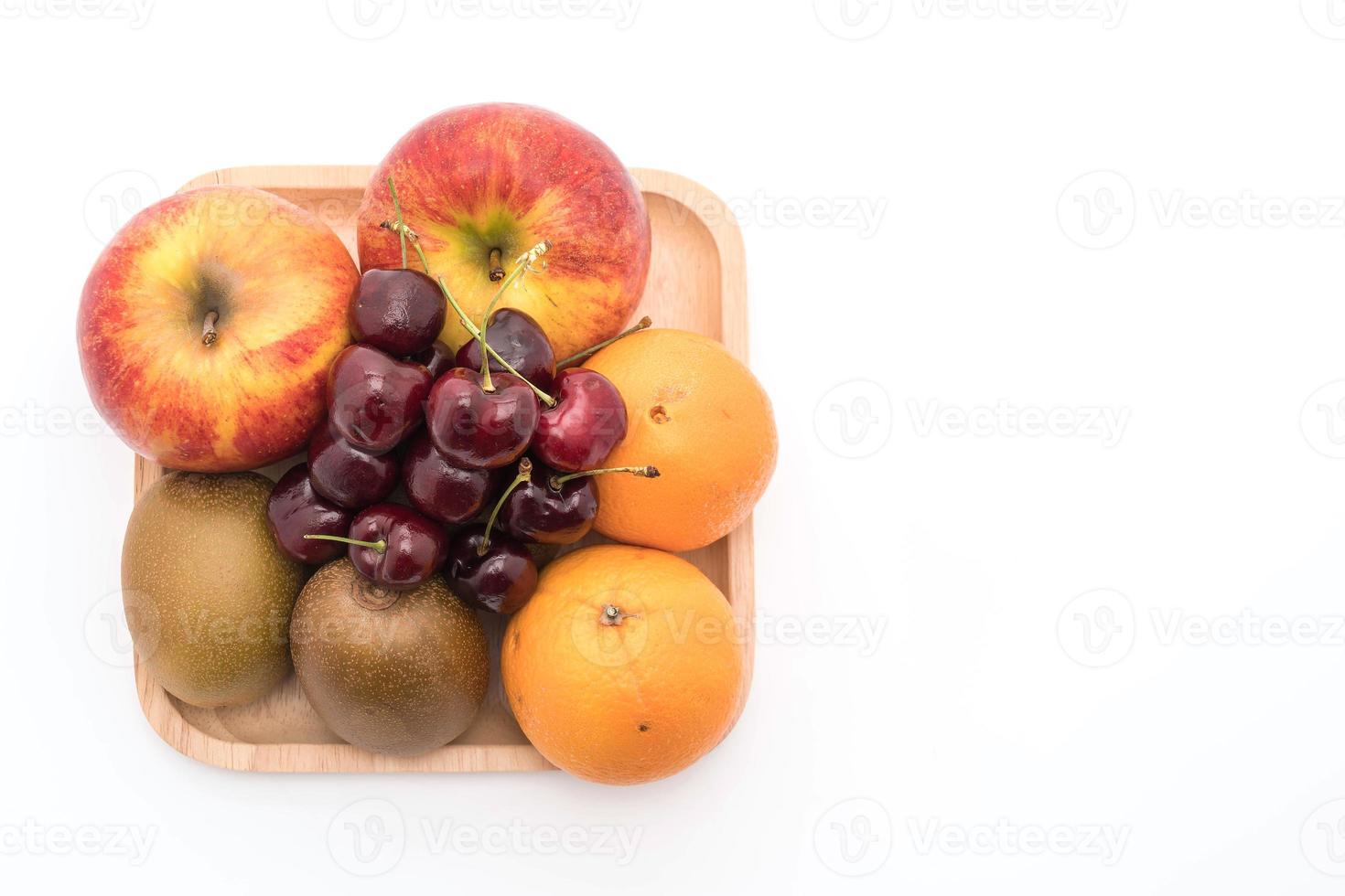 frutta mista in piatto di legno su sfondo bianco foto