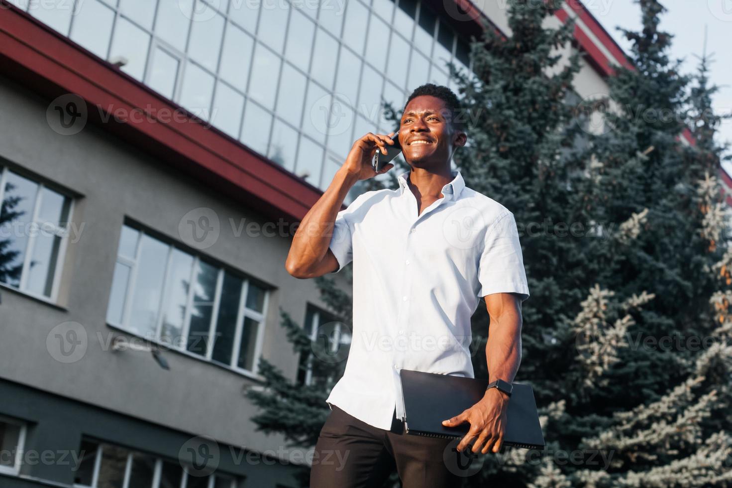 felice afroamericano con un telefono per strada foto