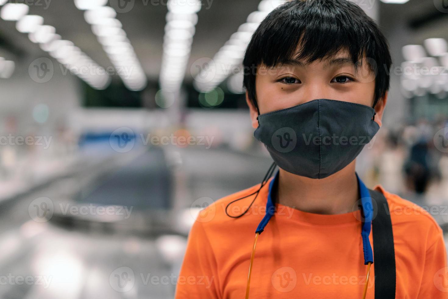 un ragazzo che indossa una maschera sanitaria per viaggiare in aeroporto foto