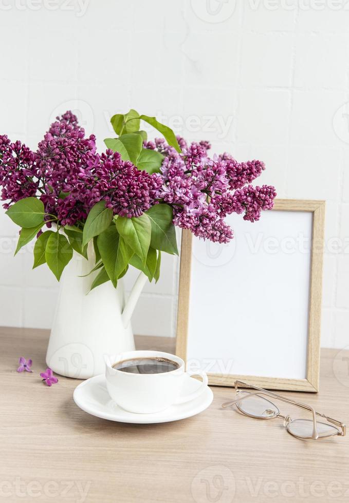 bouquet di fiori lilla in vaso e cornice di legno vuota foto