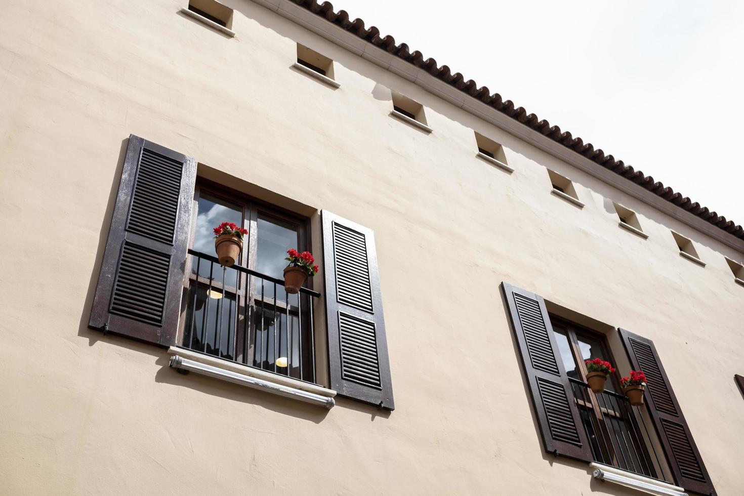 facciata a muro con due balconi in legno e vasi con fiori rossi foto