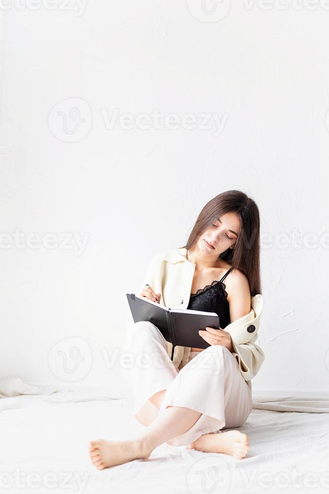 donna in abiti comodi per la casa che scrive appunti seduta sul pavimento foto