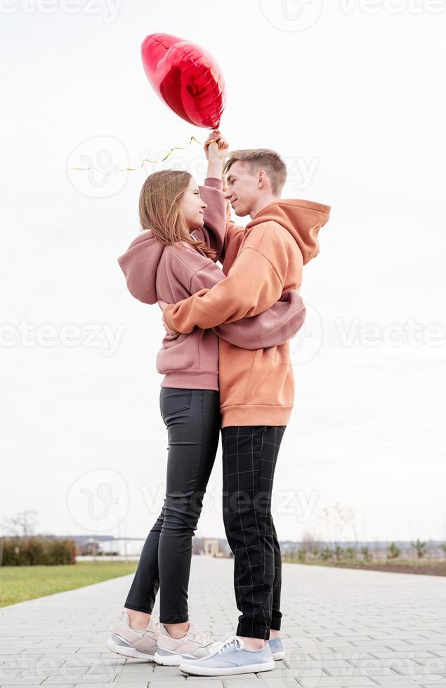 giovane coppia di innamorati con palloncini rossi che si abbracciano all'aperto divertendosi foto