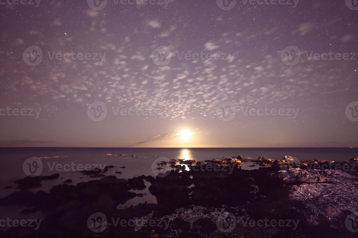 chiaro di luna e cielo stellato che illuminano l'oceano sulla grande isola, foto