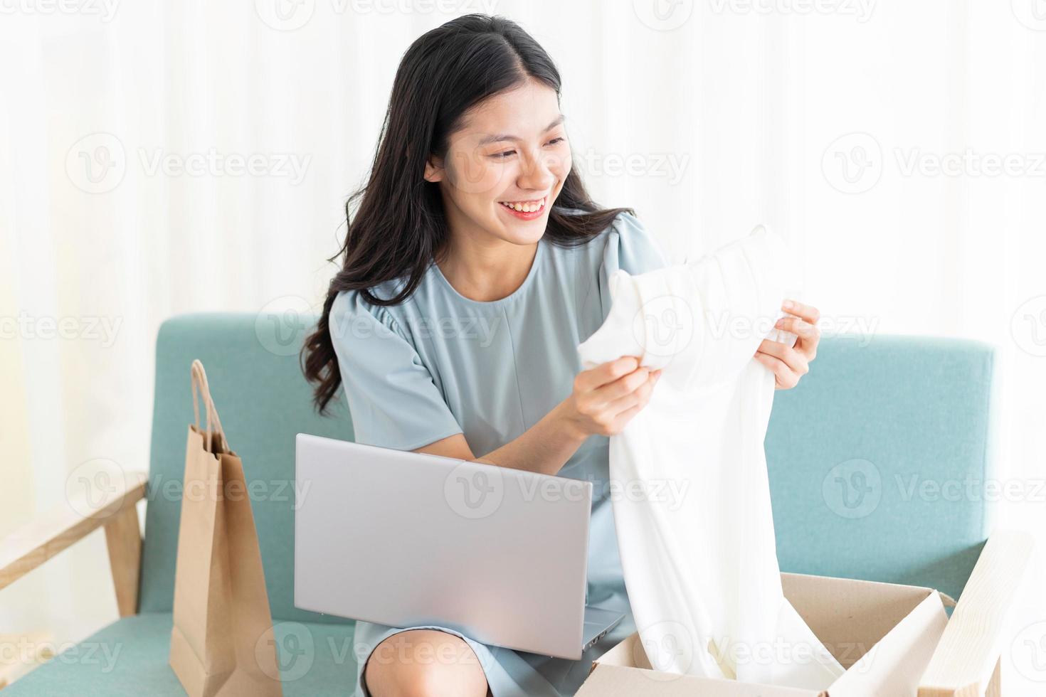 giovane ragazza asiatica seduta a casa che vende online foto