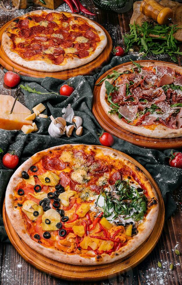 gustoso assortito tre pizze su un' di legno sfondo foto