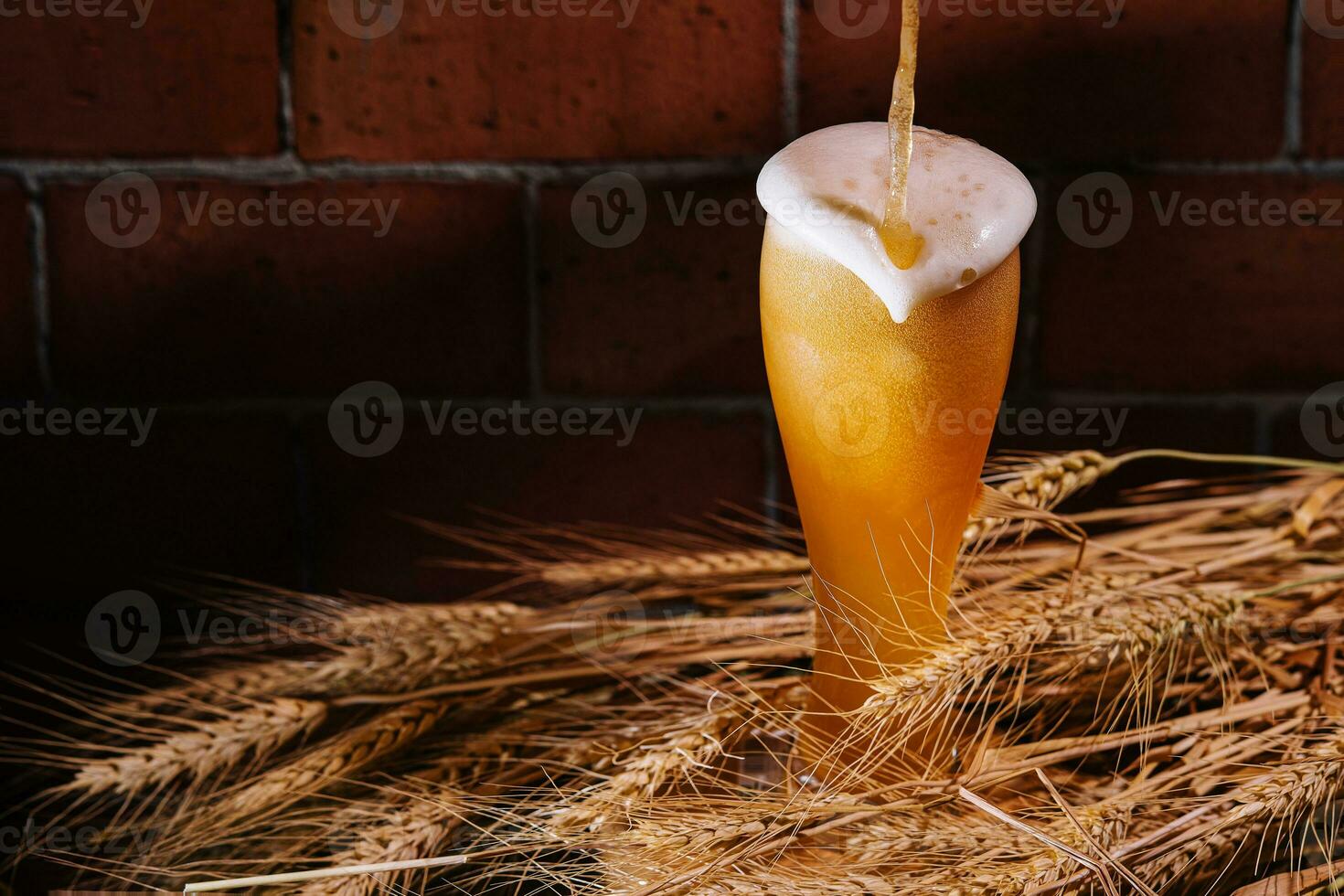 scrosciante birra in bicchiere con Grano orecchie foto