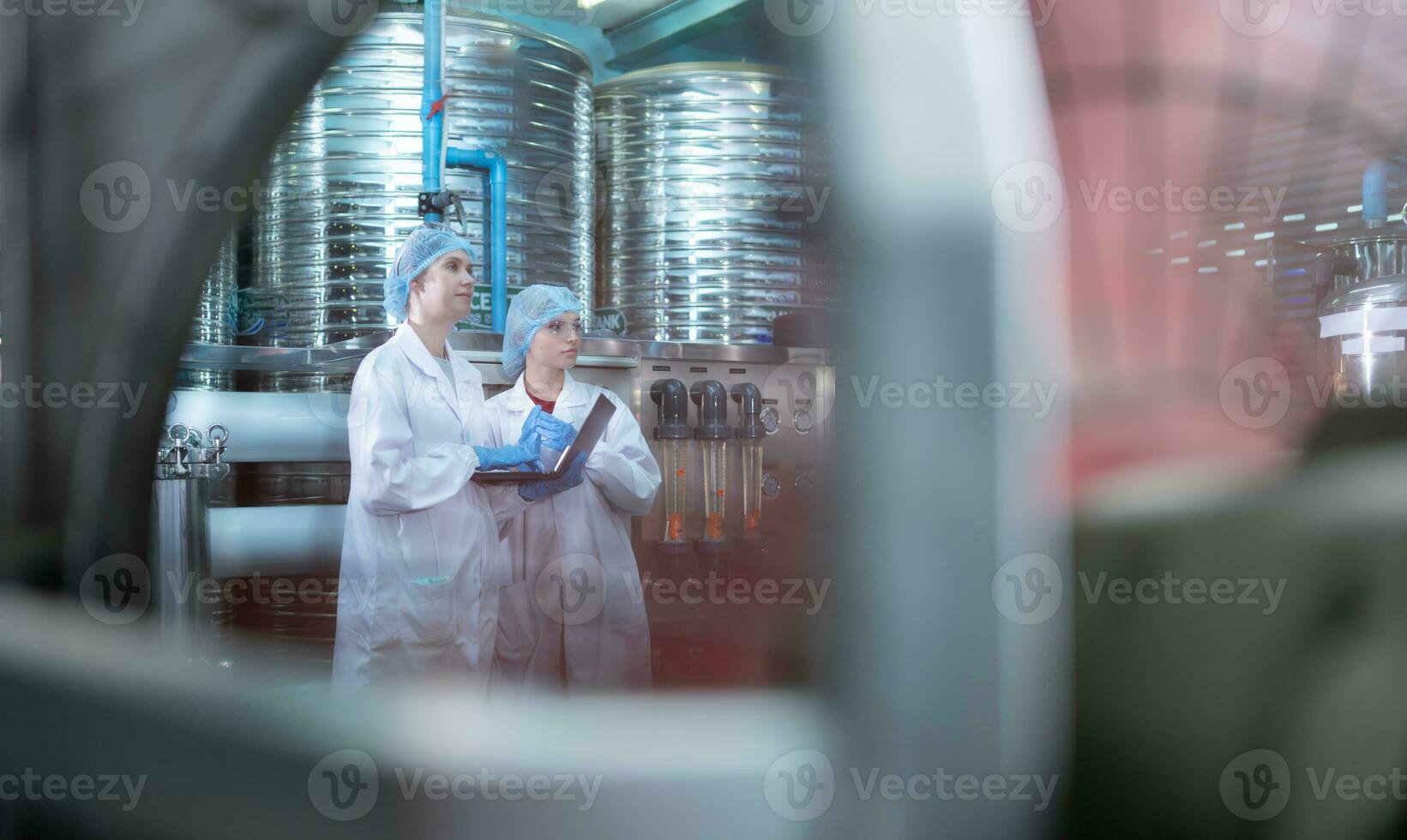 Due giovane femmina scienziati Lavorando con tavoletta computer nel potabile acqua pianta foto