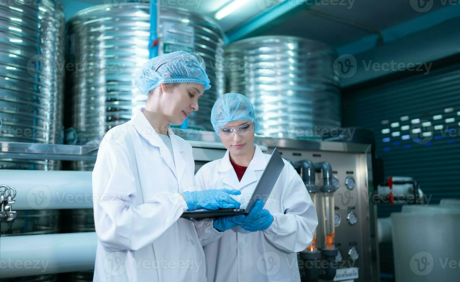 Due giovane femmina scienziati Lavorando con tavoletta computer nel potabile acqua pianta foto