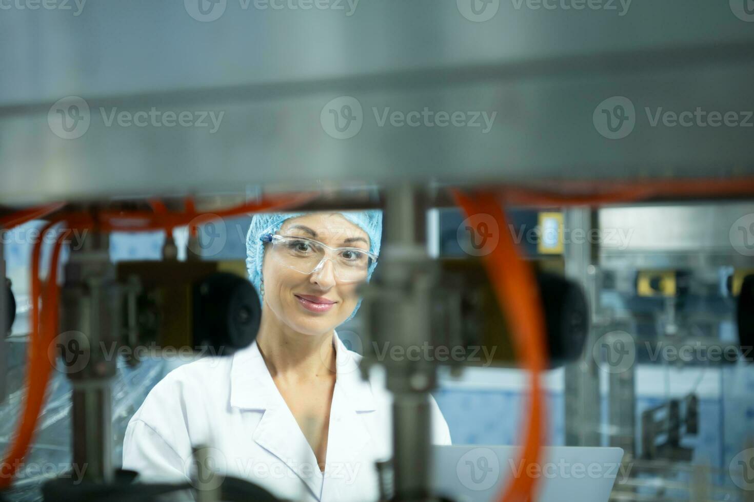 femmina scienziato nel bianca cappotto e blu cappello Lavorando nel il controllo macchina di produzione linea. foto