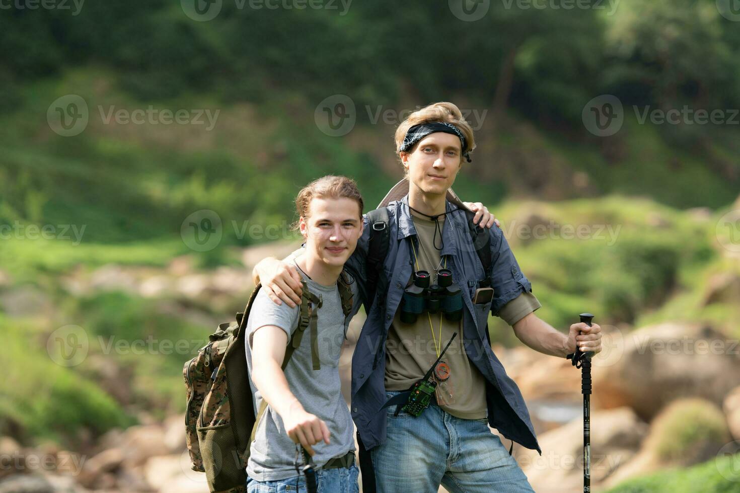 Due uomo escursioni a piedi nel il foresta con zaini e il trekking poli foto