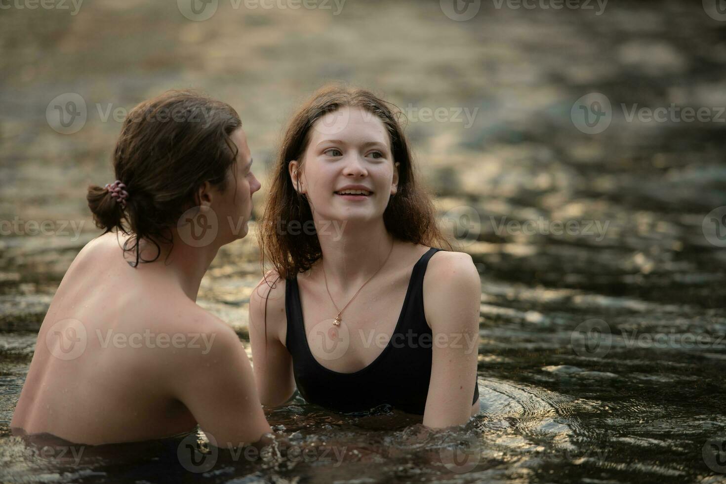 giovane coppia baci nel il mezzo di il fiume fluente nel davanti di il campeggio. foto