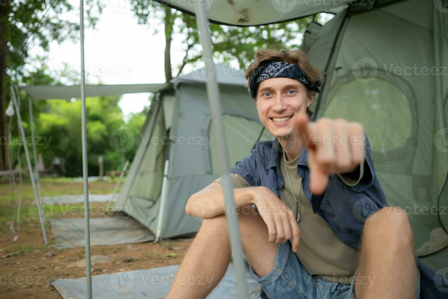 giovane uomo seduta nel davanti di tenda a campeggio nel il campagna foto