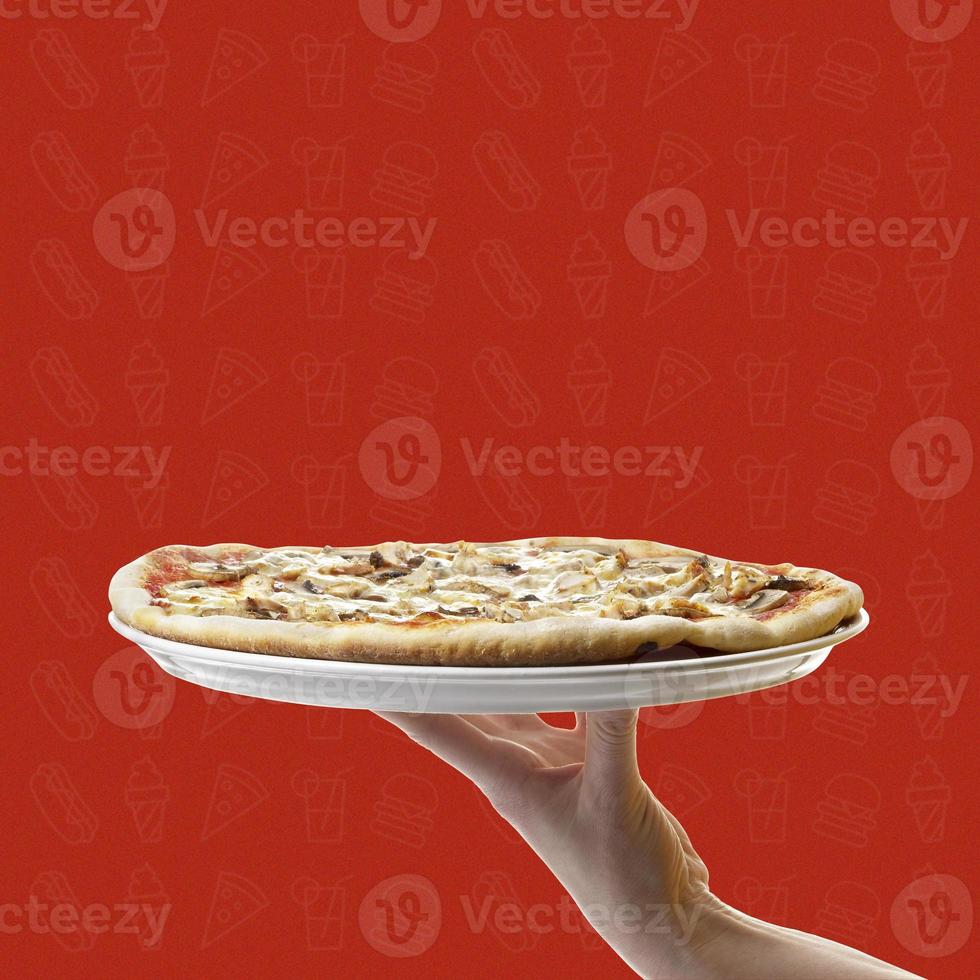 vista laterale della mano che tiene la pizza fatta in casa su sfondo rosso foto