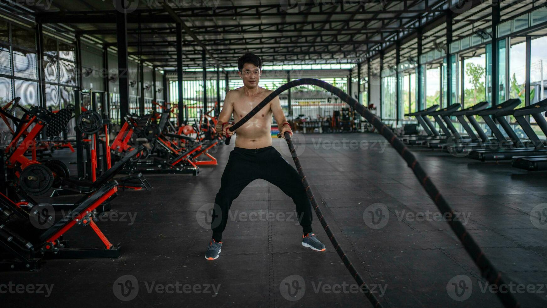 uomo fare battaglia corde esercizio nel un' fitness palestra. A petto nudo fitness giovane gli sport uomo formazione .opera su sano. esausto, stanco fuori. lotta .difficile foto