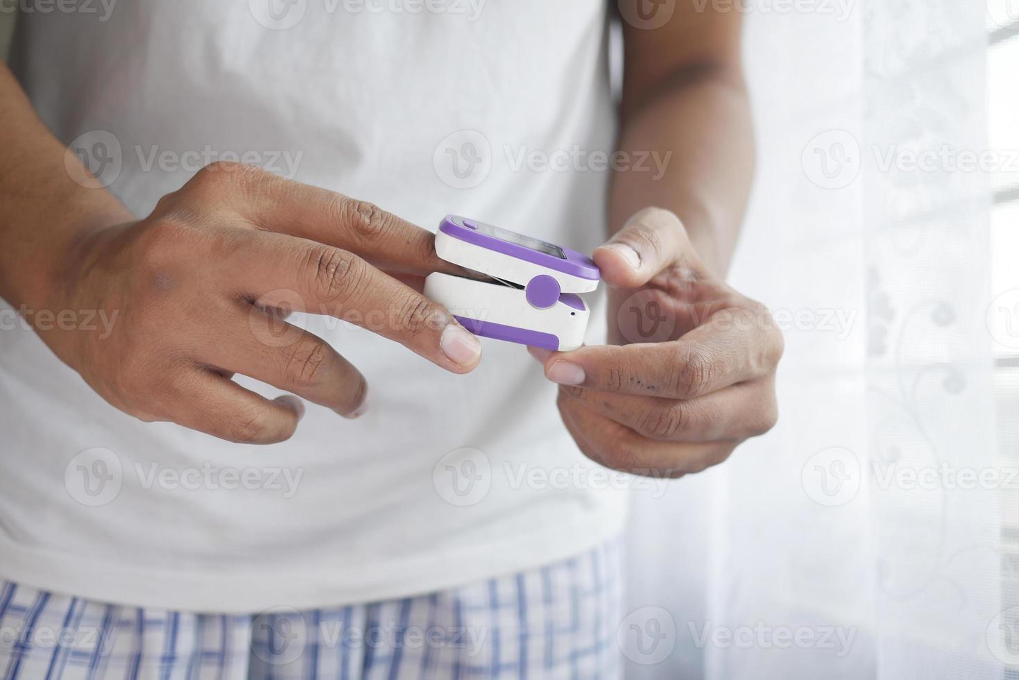 mano delle giovani donne senior usando il pulsossimetro foto