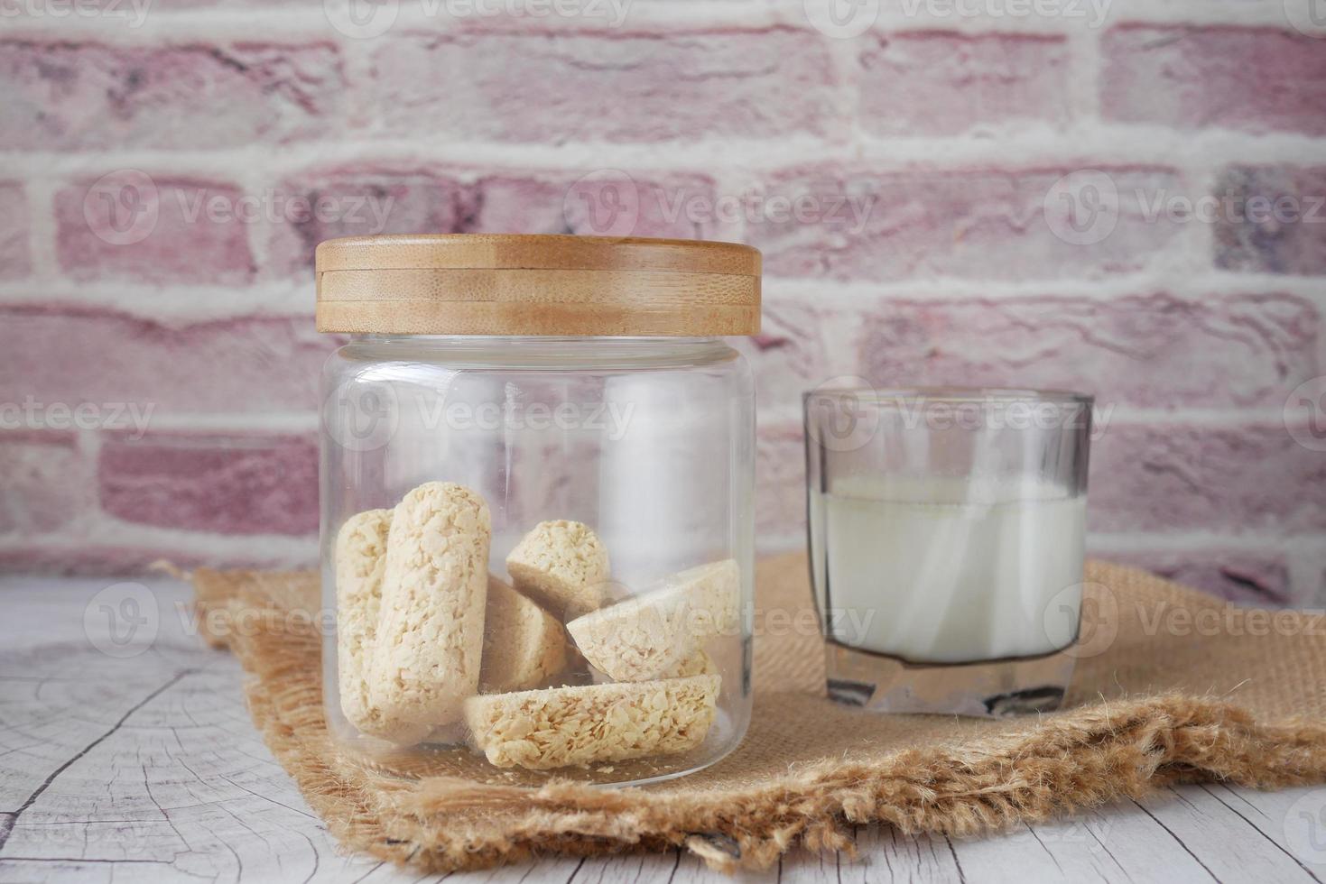 gustose barrette di avena in barattolo di vetro e latte sul tavolo foto