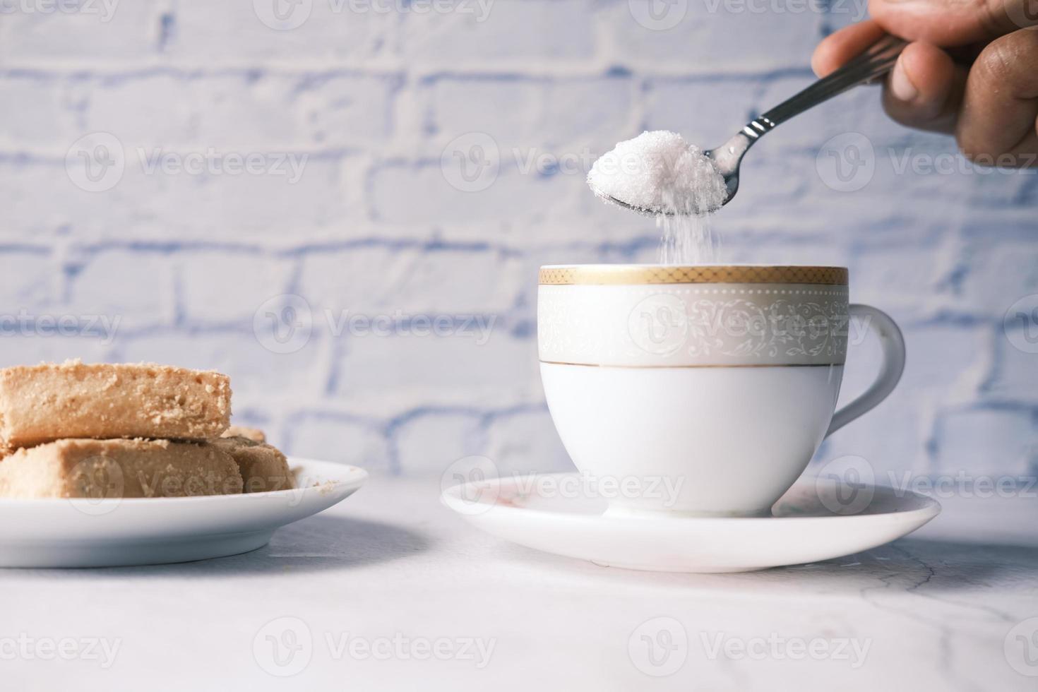 versare lo zucchero bianco in una tazza da tè foto