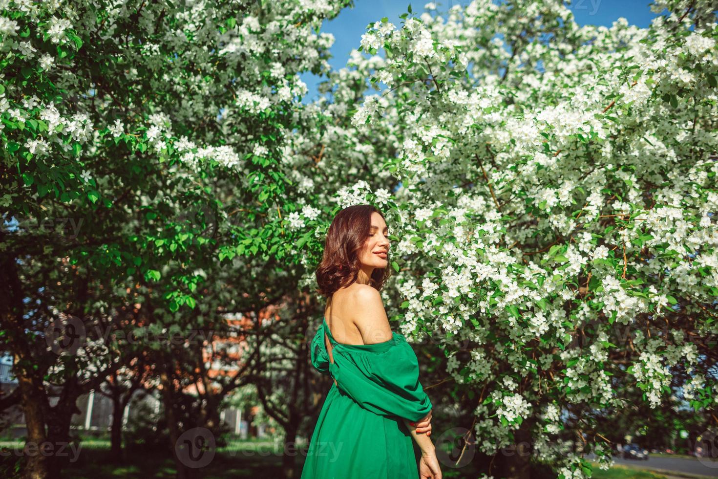 una giovane ragazza è in piedi nel parco sotto un melo in fiore foto