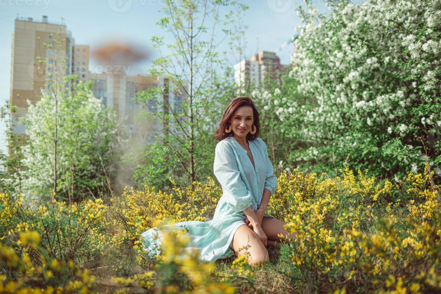 la ragazza si siede nel parco sull'erba sotto un melo bianco in fiore foto