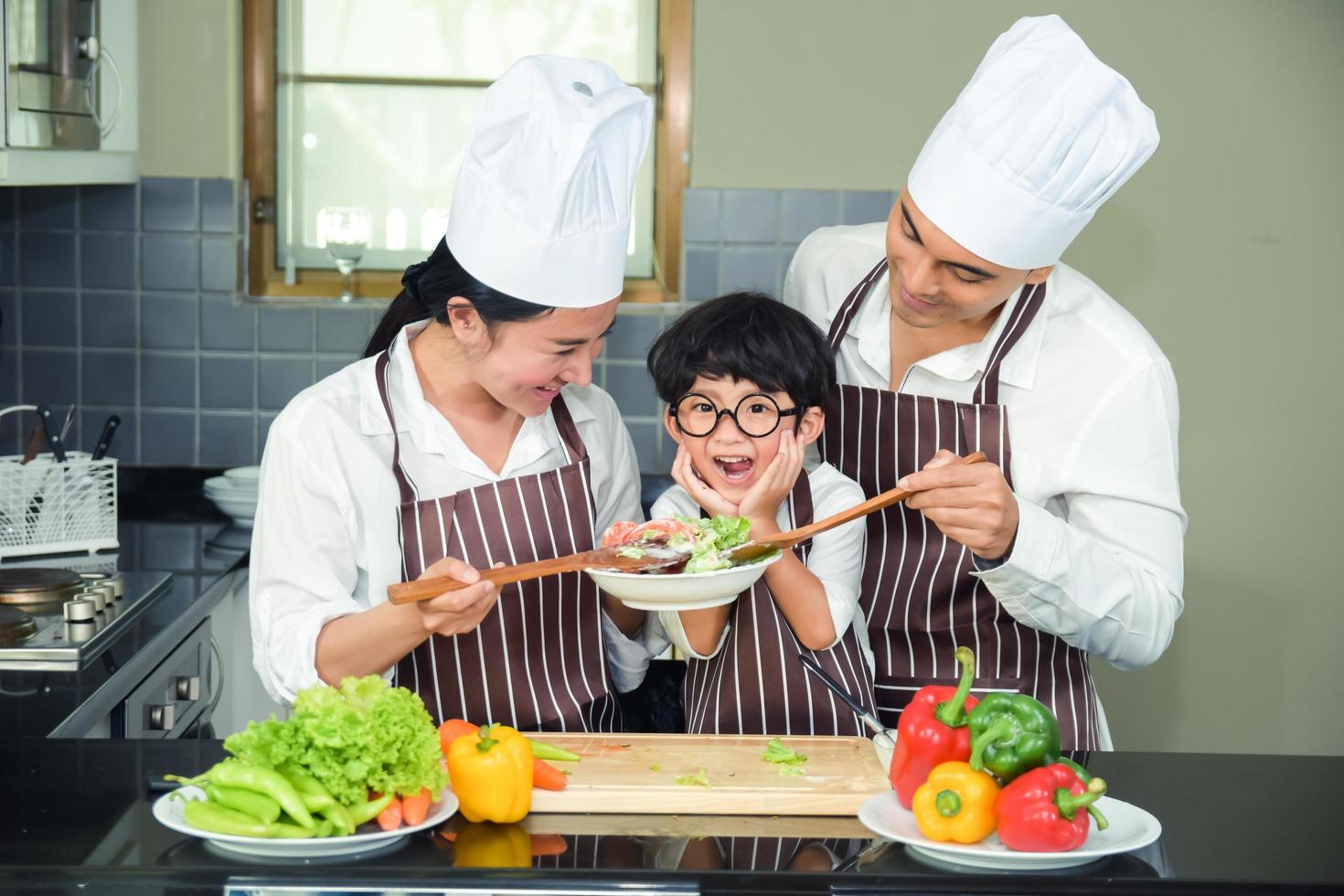 donna asiatica giovane madre con figlio ragazzo che cucina insalata foto