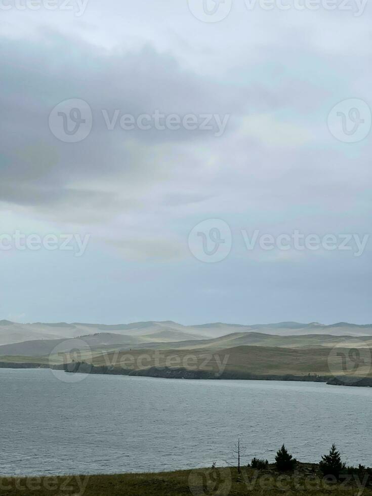 lago baikal nel il presto mattina, nebbioso foschia al di sopra di il acqua. cupo duro paesaggio foto