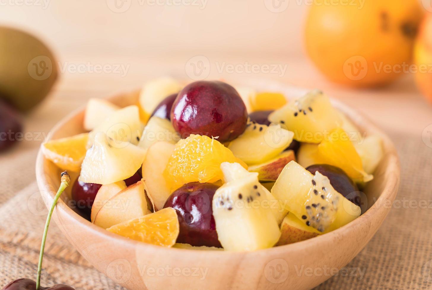 frutta mista a fette nel piatto di legno foto