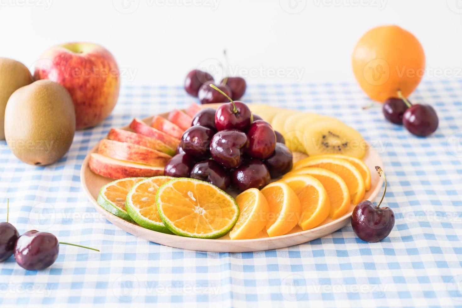 frutta mista a fette nel piatto di legno foto