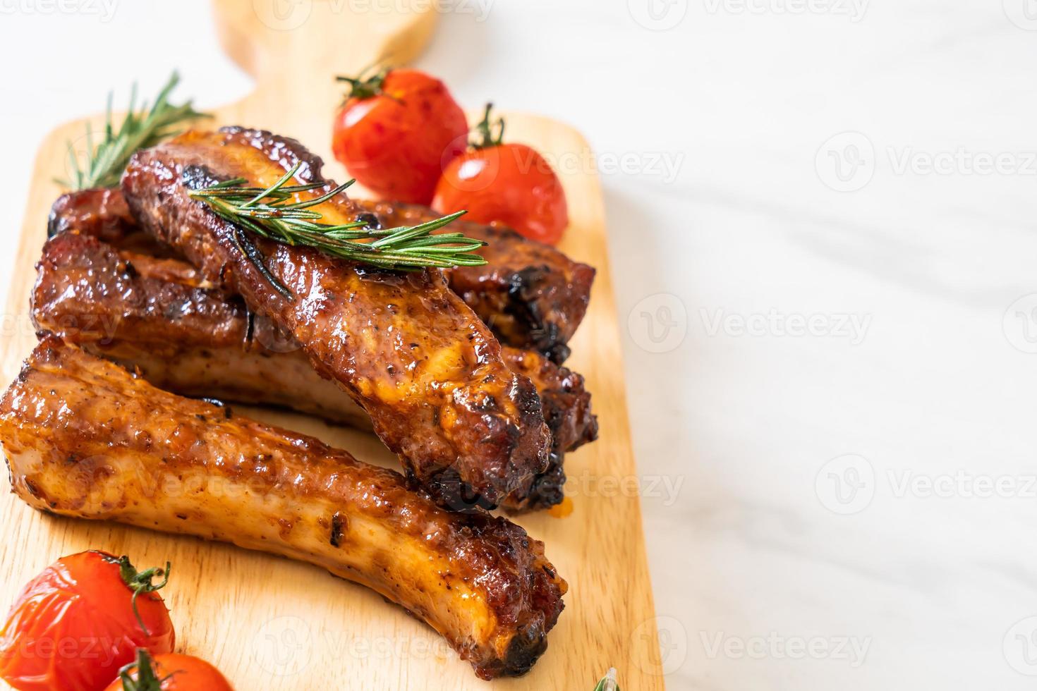 costine di maiale grigliate al barbecue con rosmarino e pomodori foto