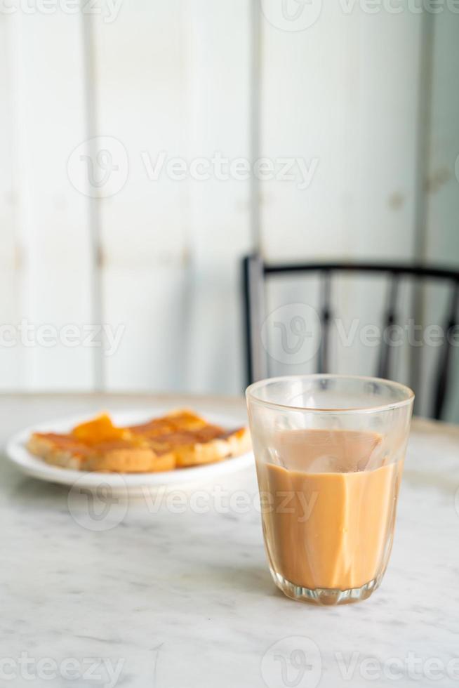 bicchiere di tè al latte tailandese caldo sul tavolo foto