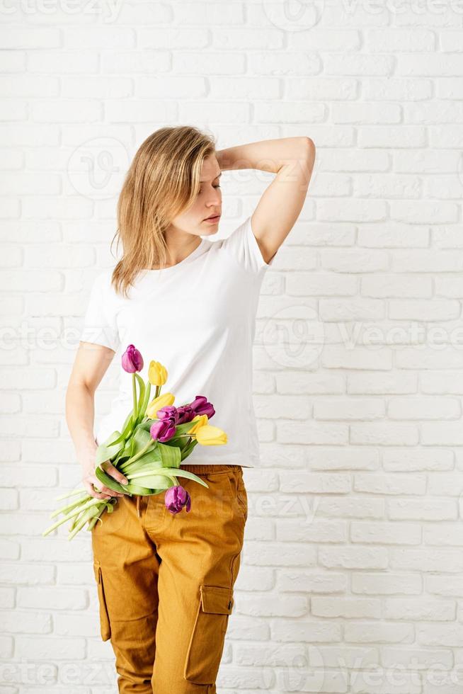 donna che indossa una maglietta bianca vuota con in mano fiori di tulipano foto