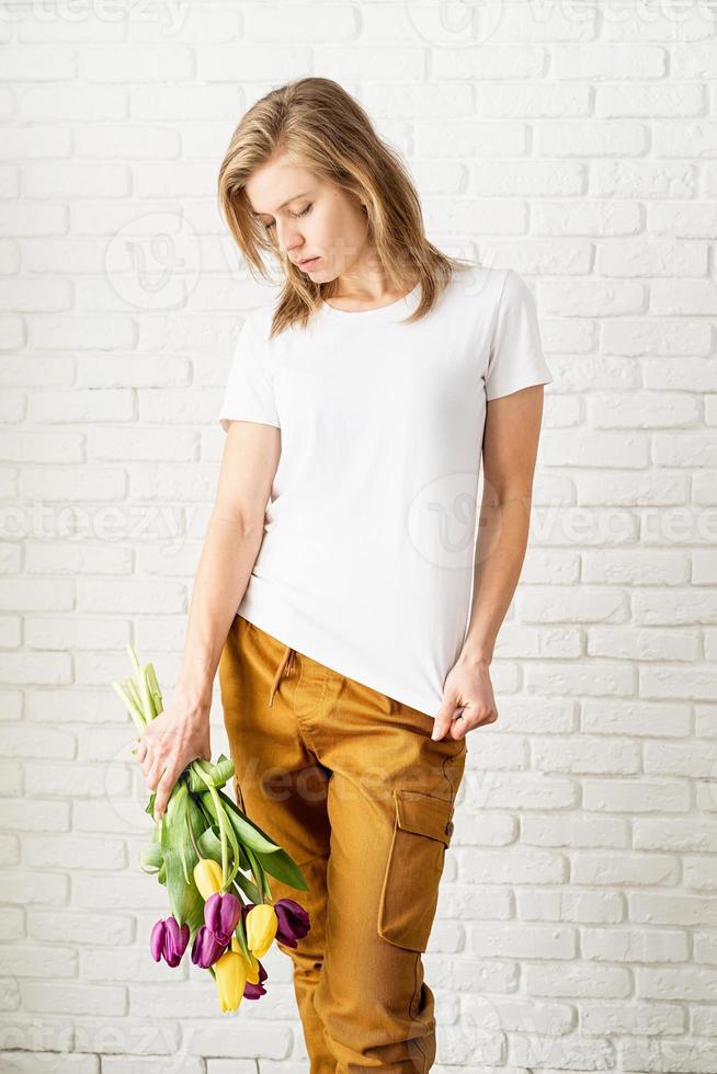 donna che indossa una maglietta bianca vuota con in mano fiori di tulipani foto