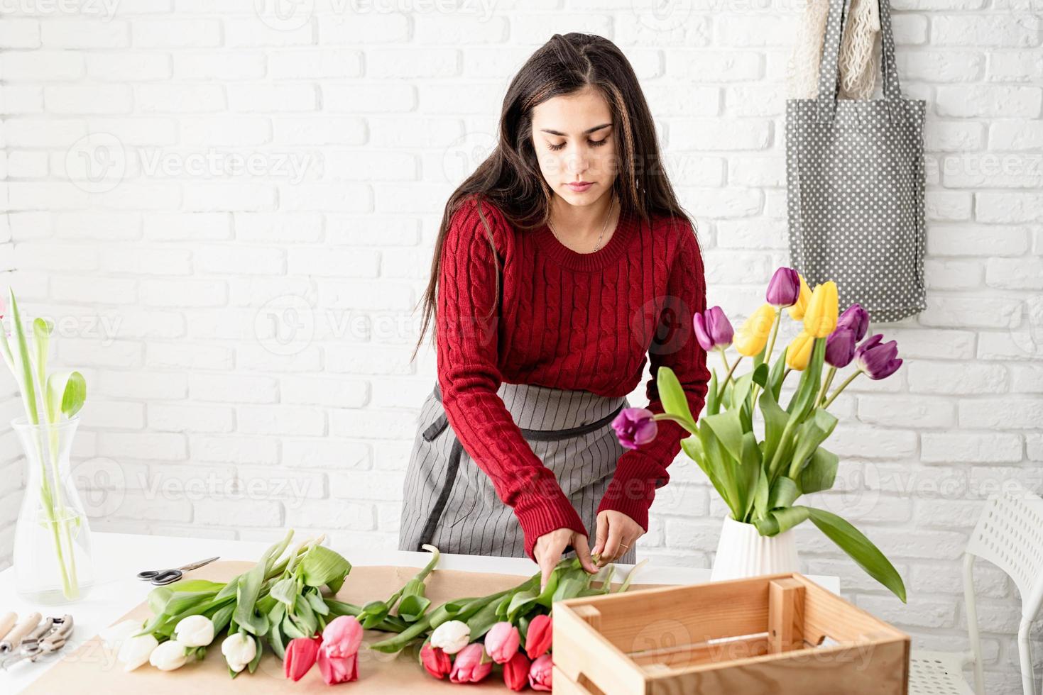 fiorista donna che fa un mazzo di tulipani freschi e colorati foto