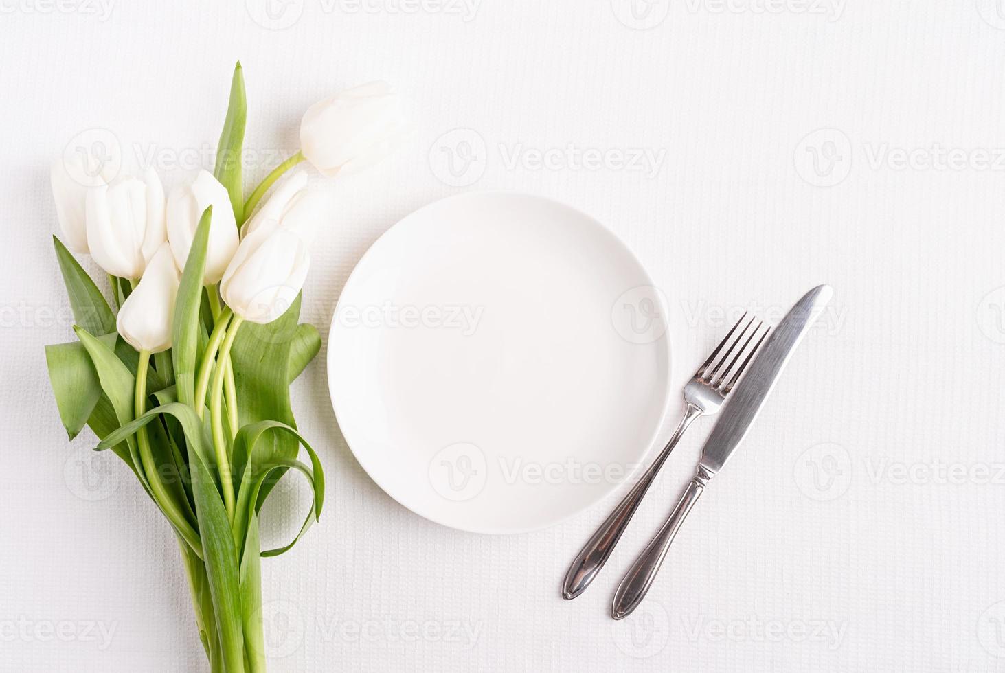 tavola festiva in bianco, piatto bianco e tulipani foto