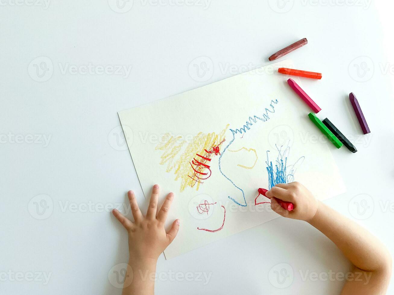 piccolo bambino disegna con pastello pastelli su bianca tavolo. foto