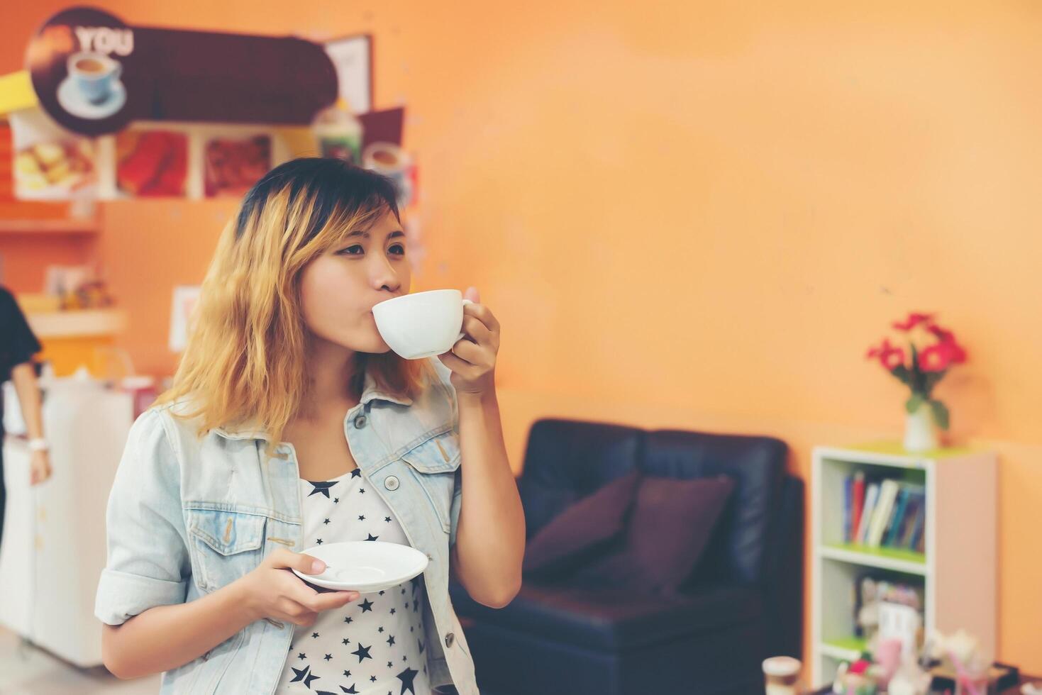 giovane bella donna che beve il caffè caldo del cappuccino al caffè. foto