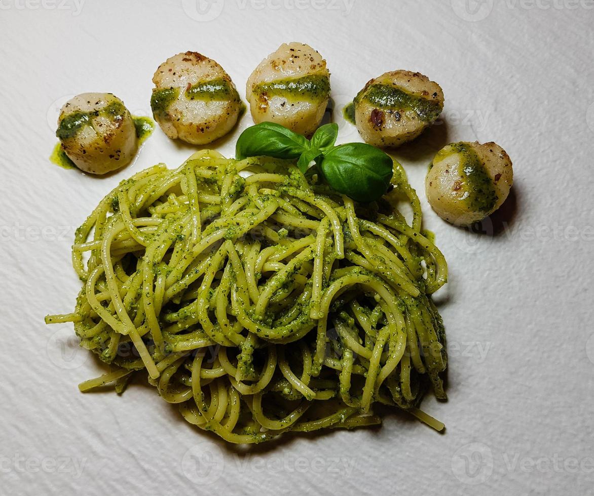 conchiglie fritte di mare su spaghetti al pesto verde foto