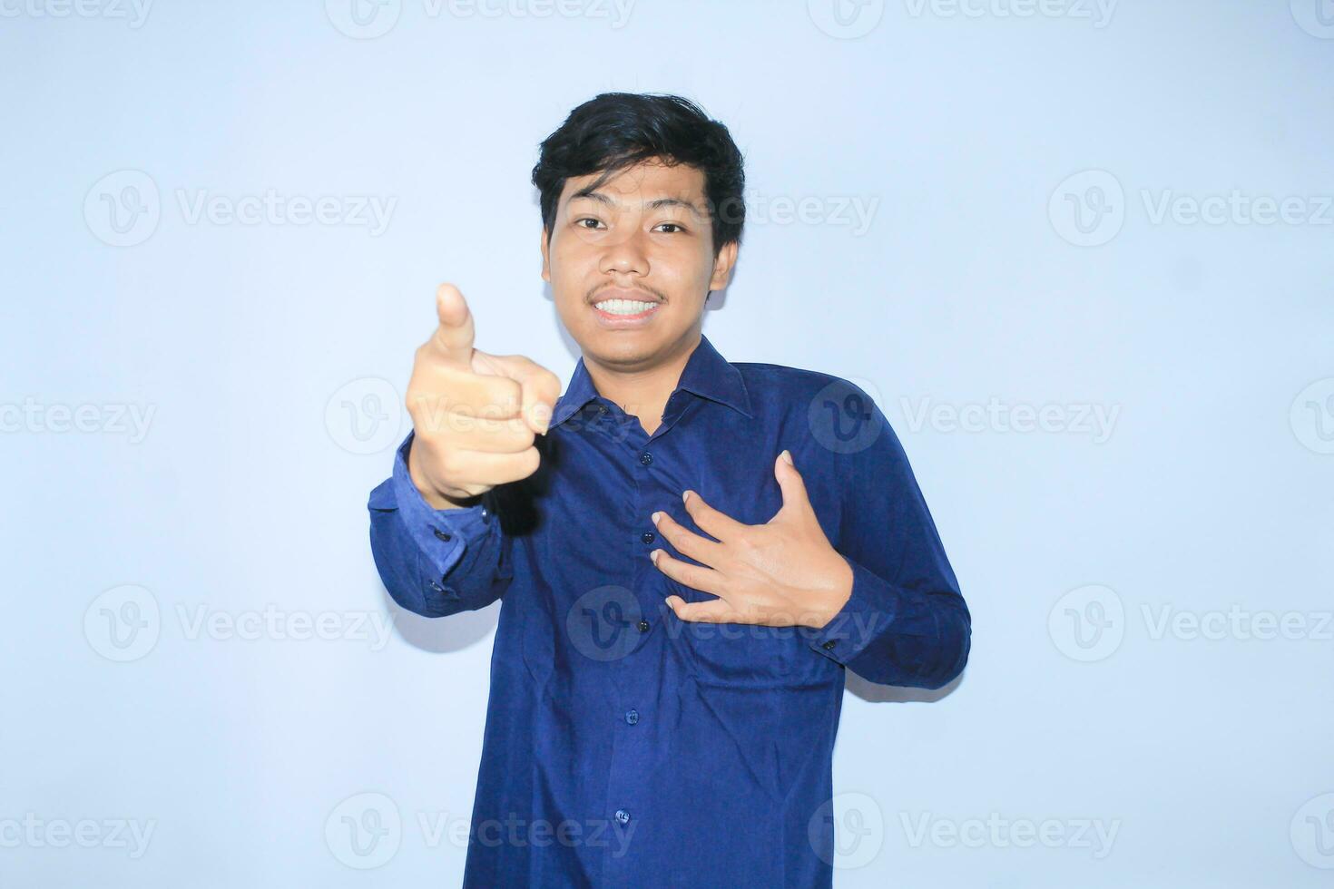 grato asiatico uomo d'affari è sorridente dopo sofferenza a partire dal cuore attacco mostrare presentazione gesto con puntamento dito per telecamera foto