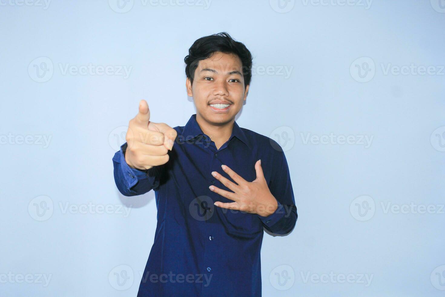 grato asiatico uomo d'affari è sorridente dopo sofferenza a partire dal cuore attacco mostrare presentazione gesto con puntamento dito per telecamera foto