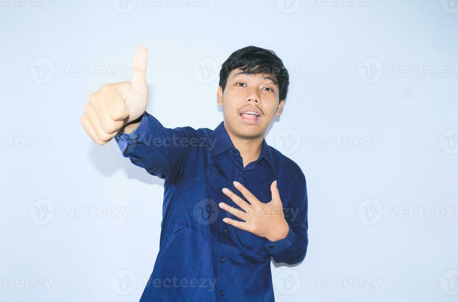 orgoglioso giovane asiatico uomo sorridente con grato viso per sopravvissuto a partire dal cuore attacco e ha recupero è Tenere il petto con pollici su indossare Marina Militare camicia foto