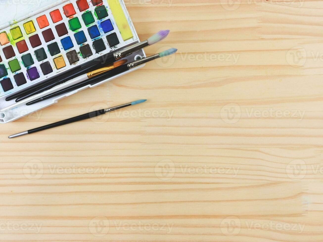 piatto posare di artista spazio di lavoro. disegno Strumenti, stazionario forniture, acquerello vernici e spazzole su di legno tavolo. foto