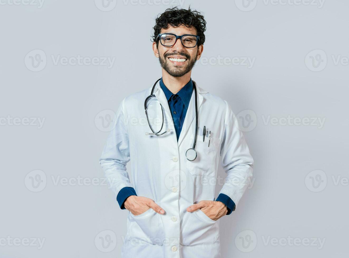 sorridente medico su isolato sfondo. contento medico con mani nel tasche. ritratto di sorridente giovane medico isolato foto