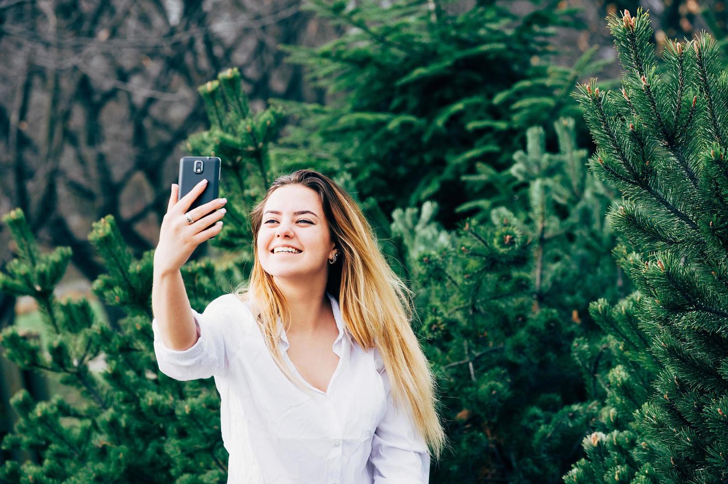 una bella giovane donna che sorride e si fa selfie in un parco foto