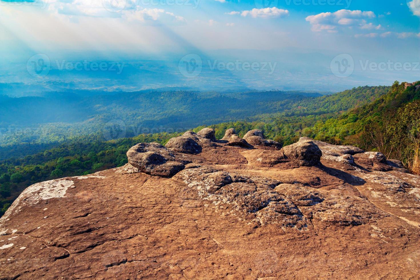 scogliera di pietra thailandese con raggio di sole e sfondo di montagna foto