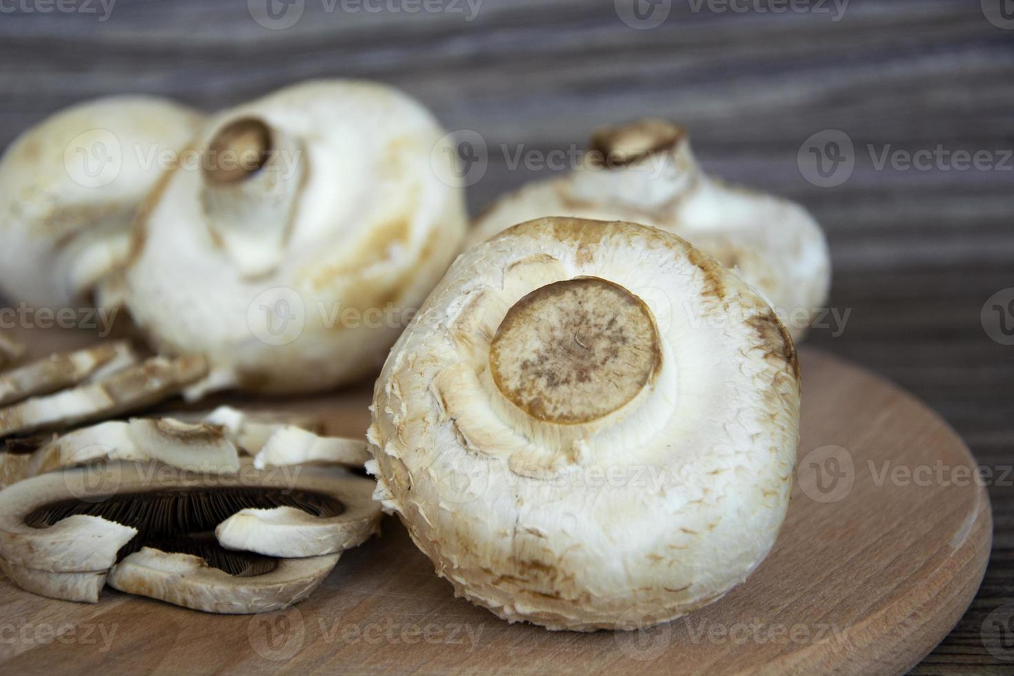 primo piano di funghi prataioli. i funghi champignon giacciono su uno sfondo di legno foto