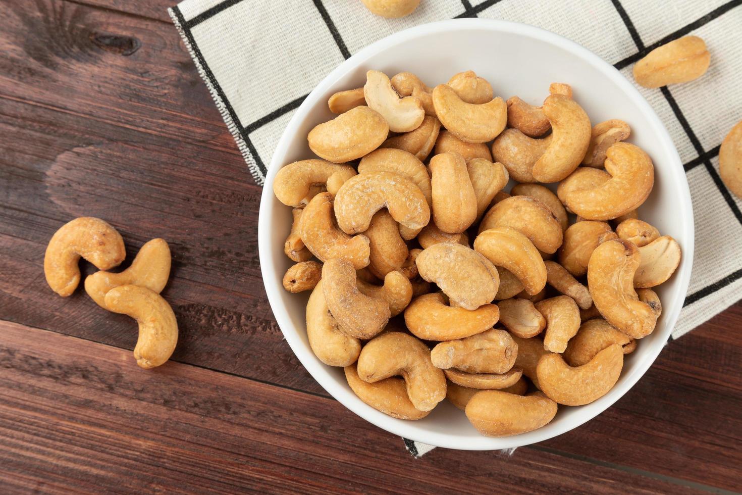 anacardi in ciotola bianca sul tavolo, spuntino sano, cibo vegetariano foto