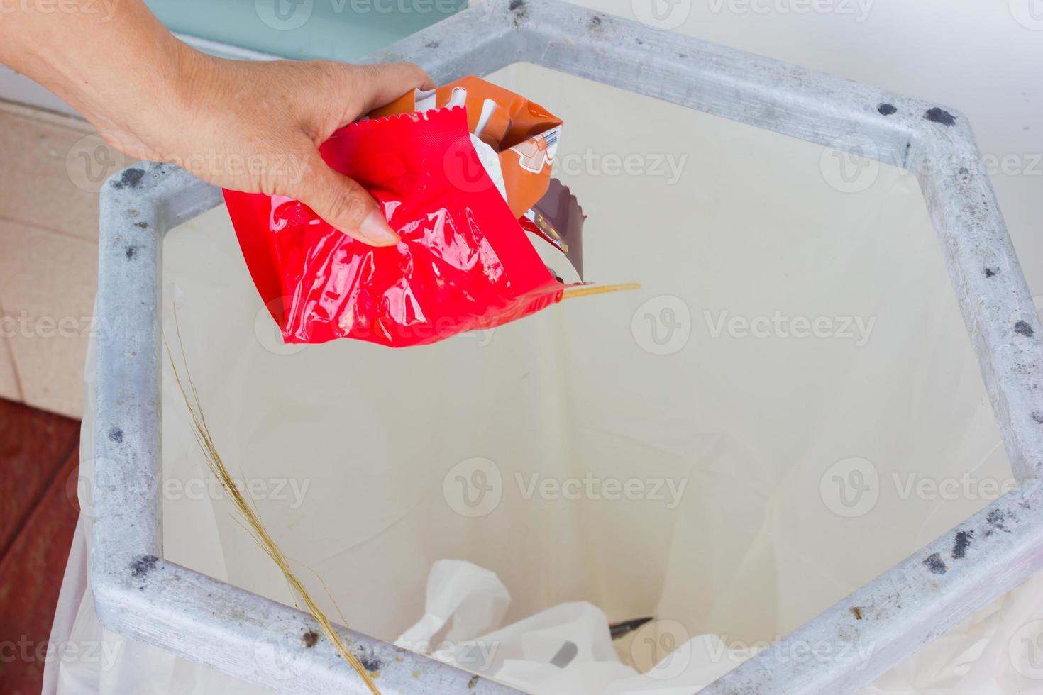 la mano del primo piano getta via il materiale di scarto rosso nel contenitore della spazzatura foto