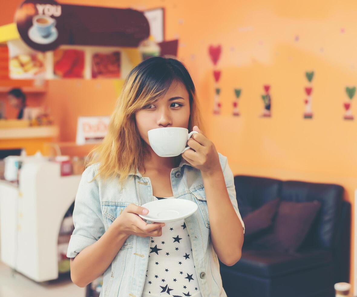 giovane bella donna che beve il caffè caldo del cappuccino al caffè. foto