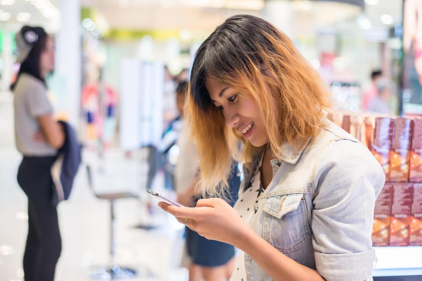 giovane bella donna sms sullo smartphone nel centro commerciale. foto